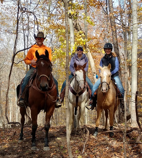 Three individuals riding horses